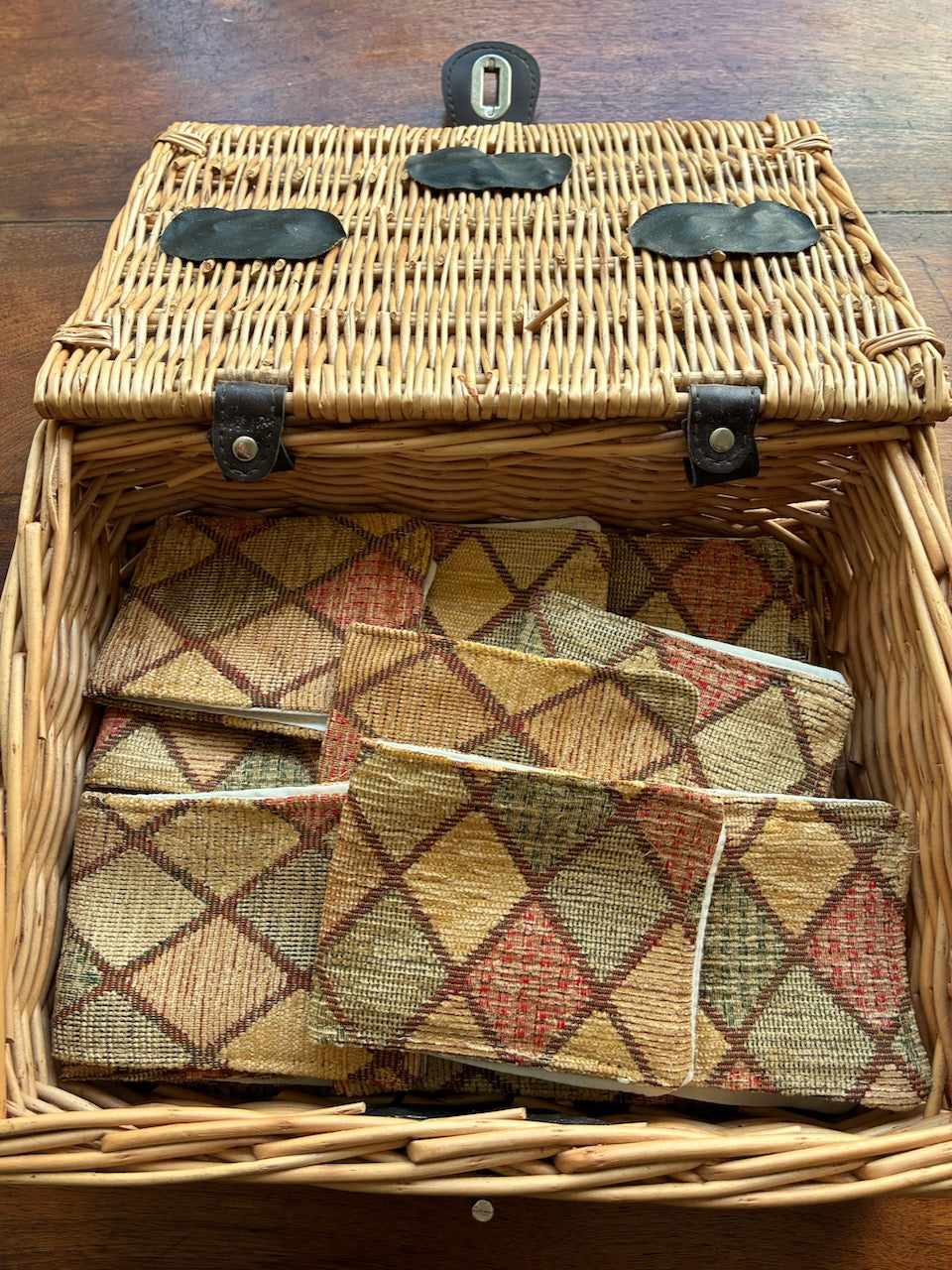 Wicker picnic basket with Harlequin Needle Cases by Curlew Crafts inside