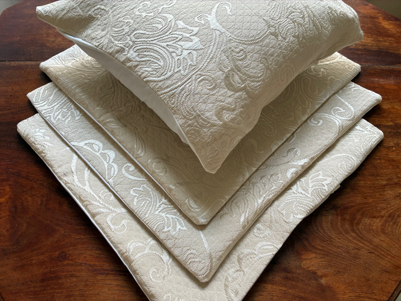 Pile of Cream Brocade Cushion Covers by Curlew Crafts. One is shown full